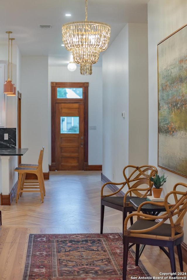 foyer with baseboards, parquet flooring, visible vents, and an inviting chandelier