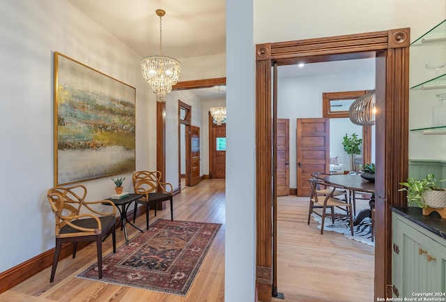 interior space featuring light wood finished floors, baseboards, and a notable chandelier