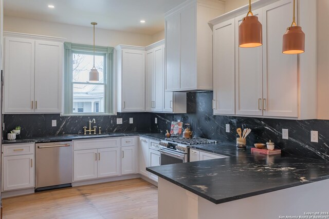 kitchen featuring appliances with stainless steel finishes, white cabinetry, tasteful backsplash, and hanging light fixtures