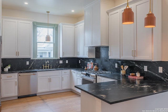 kitchen with appliances with stainless steel finishes, white cabinetry, hanging light fixtures, and light wood finished floors