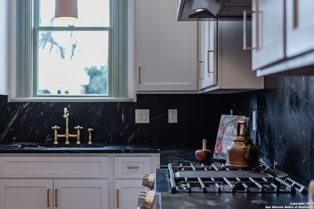 kitchen with custom exhaust hood, an inviting chandelier, backsplash, and white cabinets