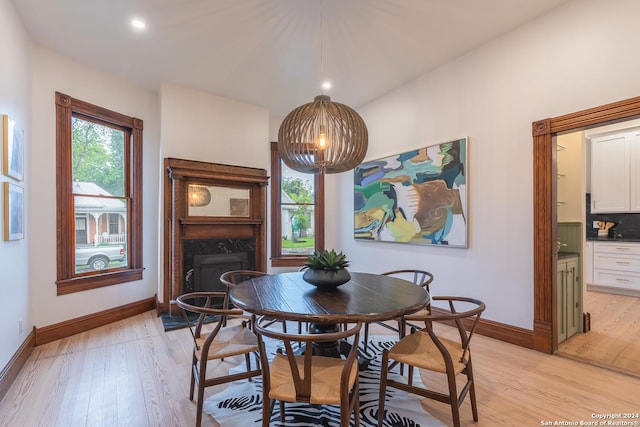 dining space with plenty of natural light, a premium fireplace, baseboards, and light wood-style flooring