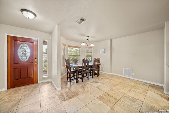 tiled foyer featuring a notable chandelier and a textured ceiling