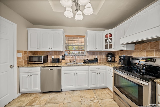 kitchen featuring appliances with stainless steel finishes, custom exhaust hood, white cabinetry, sink, and decorative backsplash