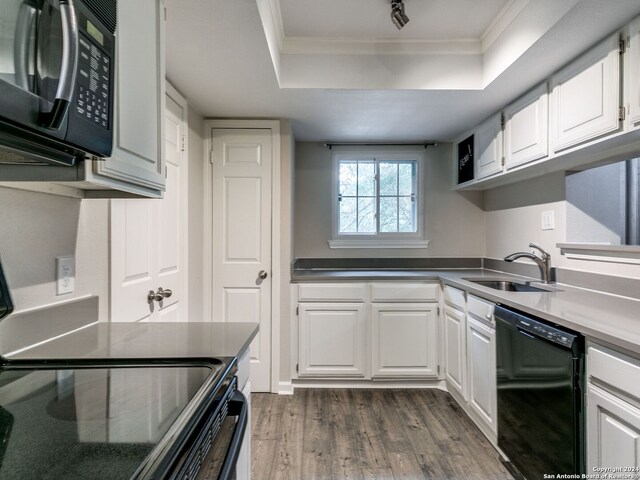 kitchen featuring black appliances, dark hardwood / wood-style flooring, sink, a tray ceiling, and white cabinets