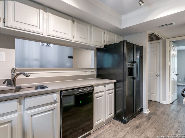 kitchen with ornamental molding, light hardwood / wood-style flooring, black appliances, sink, and white cabinets