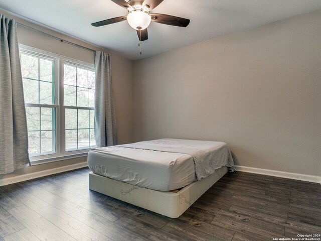 bedroom featuring ceiling fan, multiple windows, and dark hardwood / wood-style flooring