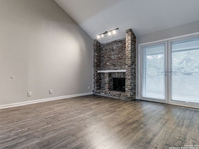 unfurnished living room featuring lofted ceiling, wood-type flooring, and a brick fireplace