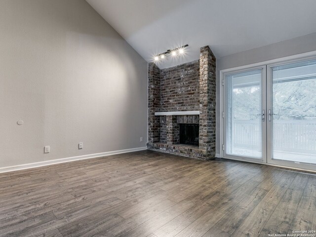 unfurnished living room with lofted ceiling, a fireplace, baseboards, and wood finished floors