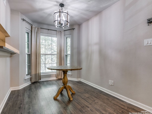 unfurnished dining area featuring dark wood-type flooring and an inviting chandelier