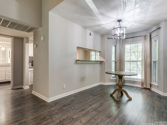 unfurnished dining area with a textured ceiling and dark hardwood / wood-style flooring