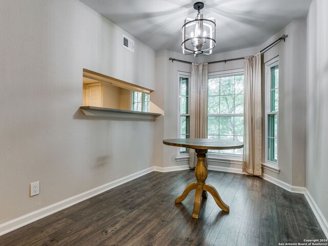 unfurnished dining area with an inviting chandelier and dark hardwood / wood-style flooring