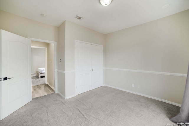 unfurnished bedroom with a closet and light colored carpet