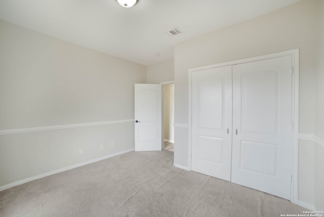 unfurnished bedroom with a closet and light carpet