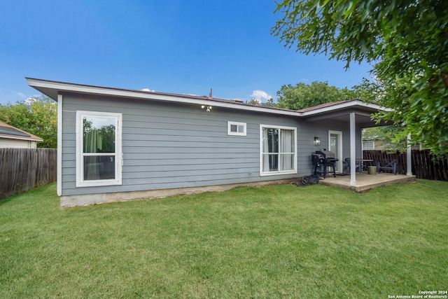 back of property with a yard and a patio