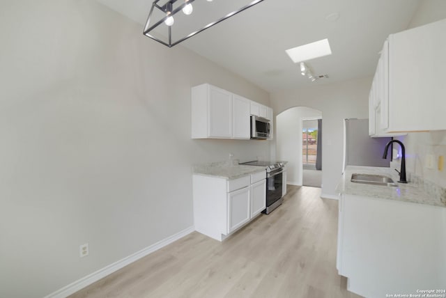 kitchen featuring light wood-type flooring, appliances with stainless steel finishes, light stone countertops, and sink