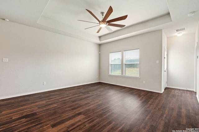 unfurnished room featuring a raised ceiling, dark hardwood / wood-style flooring, and ceiling fan