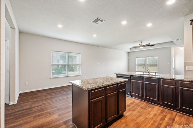 kitchen with black dishwasher, hardwood / wood-style floors, a kitchen island, and ceiling fan