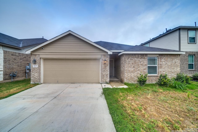 view of front of home with brick siding, driveway, a front lawn, and a garage