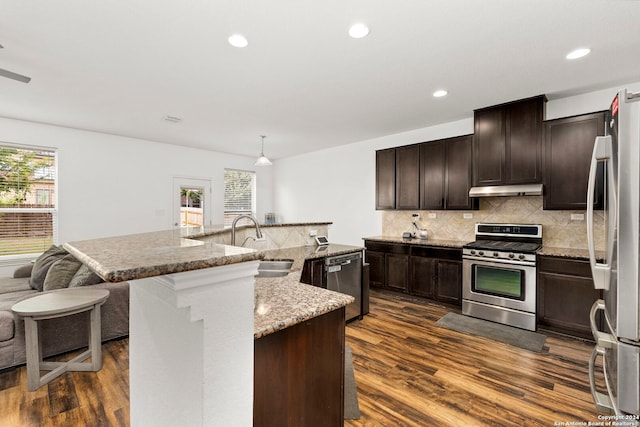 kitchen featuring an island with sink, dark wood-type flooring, stainless steel appliances, and sink