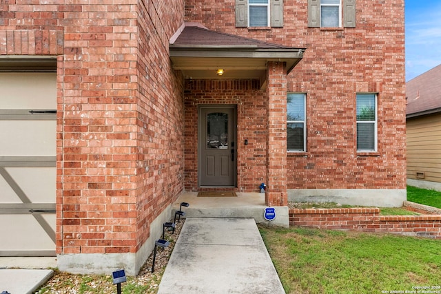 entrance to property featuring a garage and brick siding