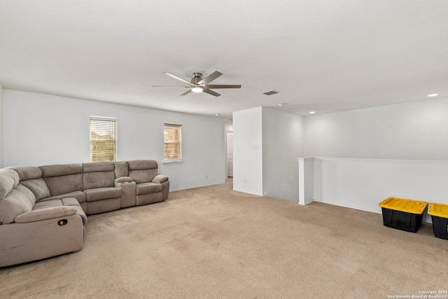 living room with a textured ceiling, ceiling fan, and light carpet