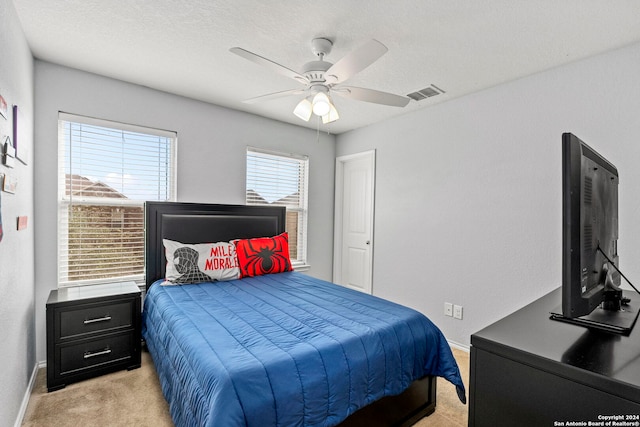 bedroom featuring a textured ceiling, ceiling fan, and light carpet