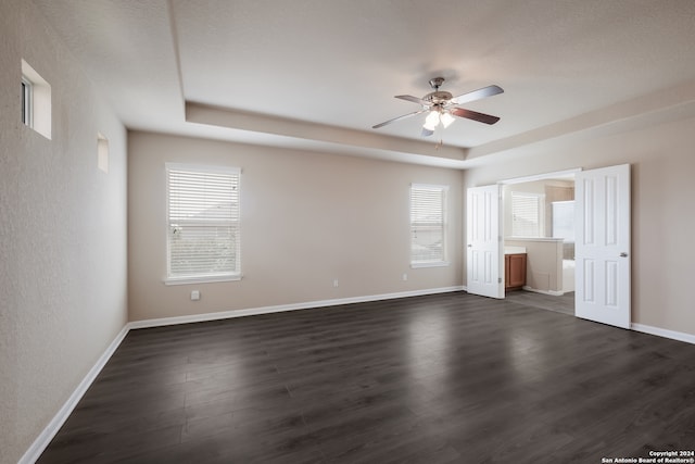 interior space featuring a textured ceiling, a raised ceiling, dark hardwood / wood-style floors, connected bathroom, and ceiling fan