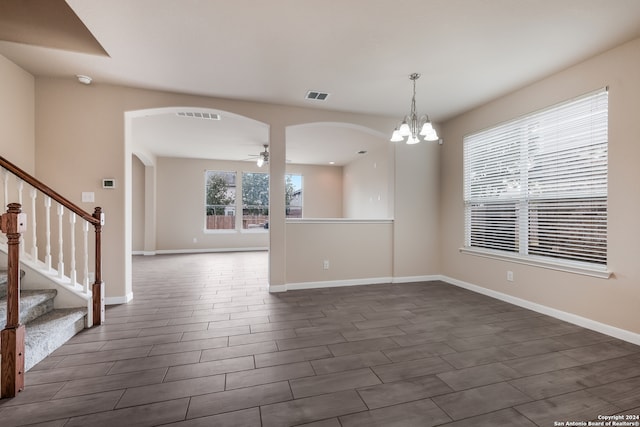 empty room with dark hardwood / wood-style floors and ceiling fan with notable chandelier