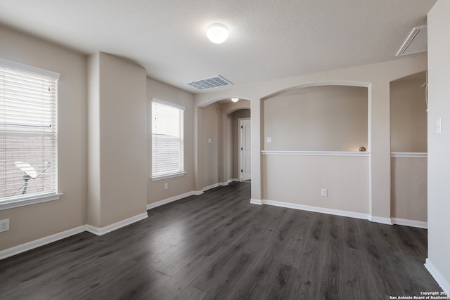 spare room with a textured ceiling and dark wood-type flooring