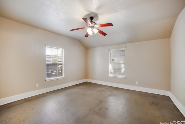 unfurnished room featuring concrete floors, ceiling fan, vaulted ceiling, and a textured ceiling