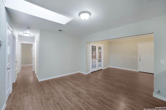 empty room with french doors, wood finished floors, visible vents, and baseboards