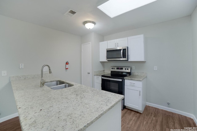 kitchen featuring stainless steel appliances, visible vents, a sink, wood finished floors, and a peninsula