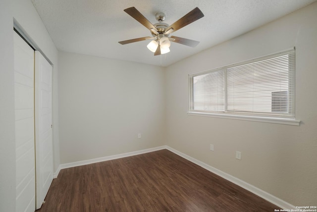 unfurnished bedroom featuring dark wood-type flooring, a closet, a textured ceiling, and baseboards