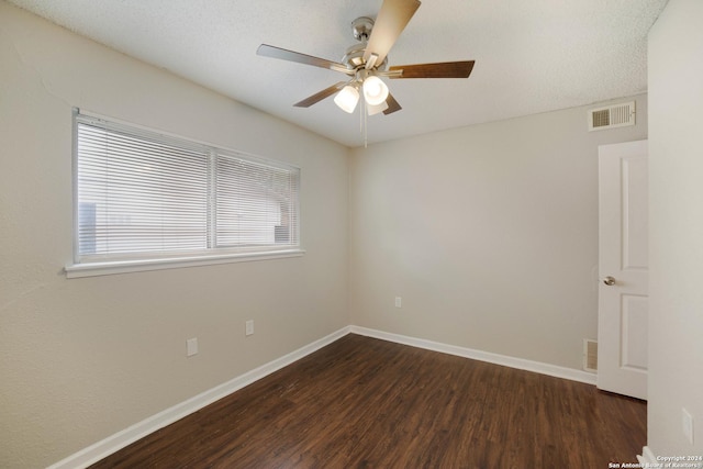 spare room with a ceiling fan, baseboards, visible vents, and dark wood-style flooring