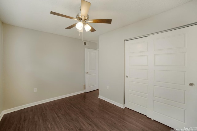 unfurnished bedroom with dark wood-style floors, a closet, visible vents, ceiling fan, and baseboards