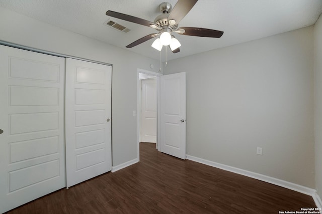 unfurnished bedroom featuring dark wood-style flooring, a closet, visible vents, ceiling fan, and baseboards