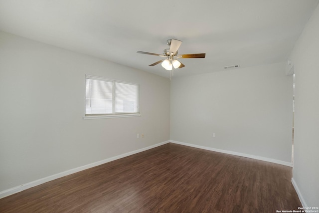 empty room featuring a ceiling fan, dark wood finished floors, visible vents, and baseboards