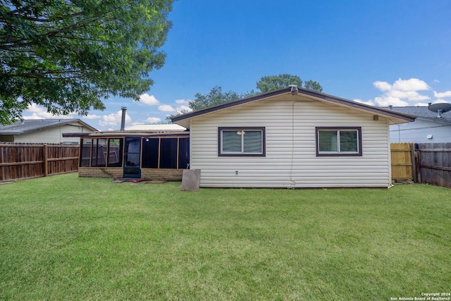 rear view of property featuring a sunroom, a fenced backyard, and a lawn