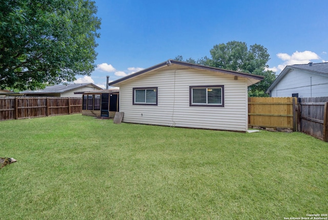 back of house with a fenced backyard and a yard