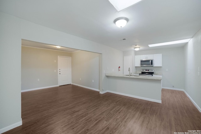 kitchen featuring stainless steel appliances, a skylight, a sink, and white cabinets