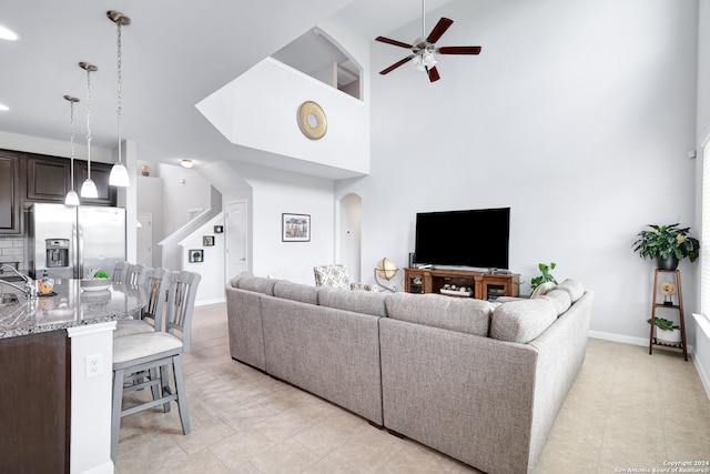 living room featuring light tile patterned floors, a high ceiling, and ceiling fan