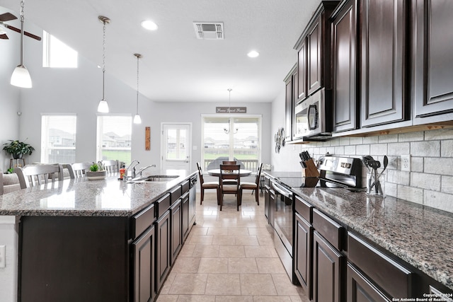 kitchen featuring an island with sink, hanging light fixtures, sink, and appliances with stainless steel finishes