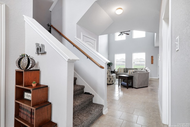 stairs featuring high vaulted ceiling, ceiling fan, and tile patterned floors