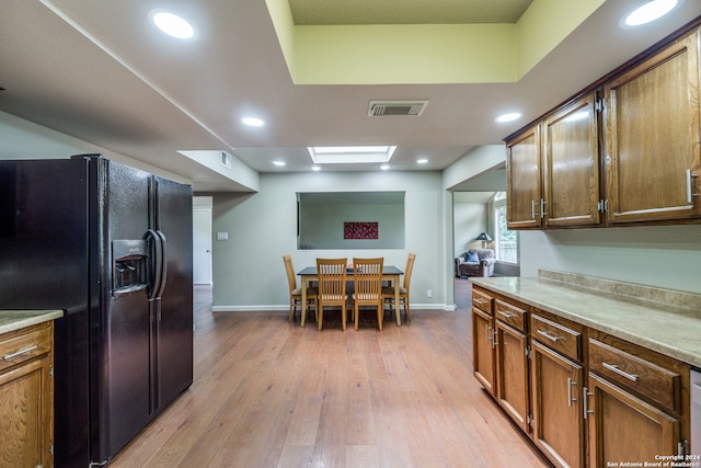 kitchen with light hardwood / wood-style flooring and black fridge with ice dispenser