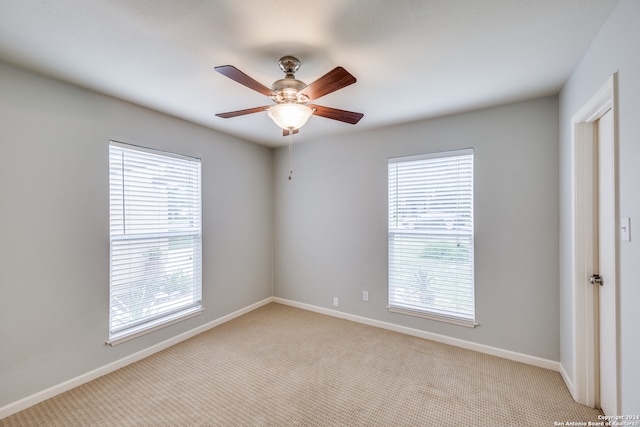 carpeted spare room featuring ceiling fan and plenty of natural light