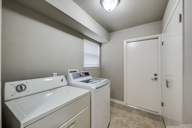 laundry room featuring light tile patterned floors, washer and clothes dryer, and a textured ceiling