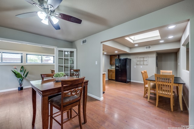 dining area with a skylight, ceiling fan, and wood-type flooring