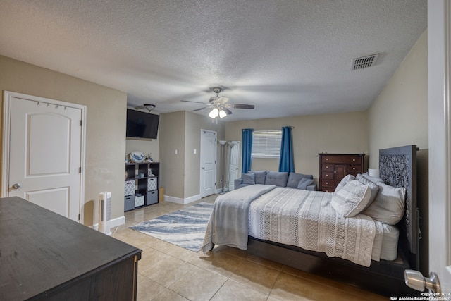 tiled bedroom with ceiling fan and a textured ceiling