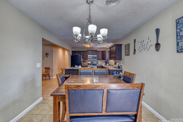 tiled dining area featuring sink, a textured ceiling, and an inviting chandelier